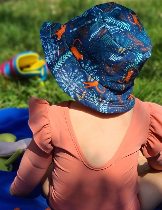 Chapeau bob réversible sur un bébé avec un maillot de bain anti UV saumon